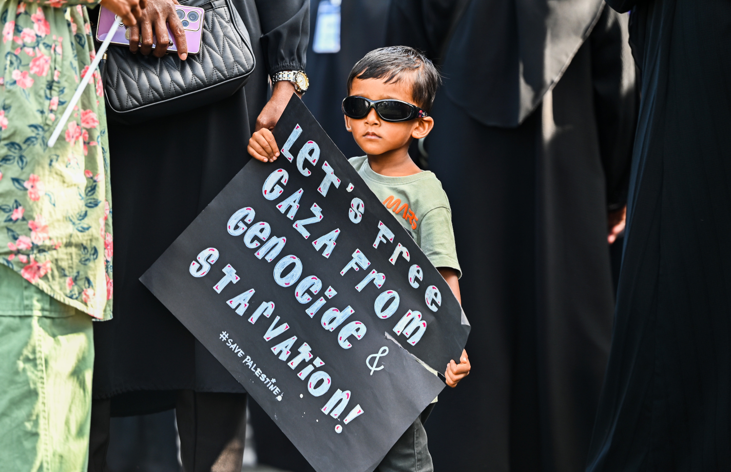 އިޒްރޭލުގެ ޖަރީމާތަކާ ދެކޮޅަށް މާލޭގައި ބޭއްވި ބޮޑު އެއްވުމުގައި ބައިވެރިވި ކުޑަކުއްޖަކު ޕޯސްޓަރެއް ހިފައިގެން.--- ފޮޓޯ: ފަޔާޒު މޫސާ | މިހާރު