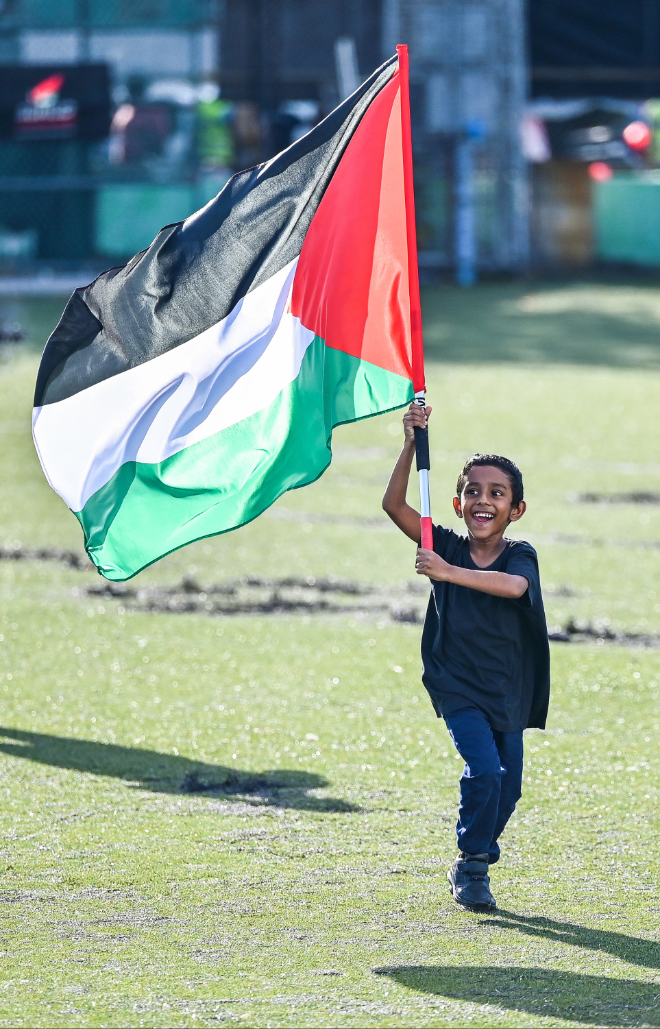 އިޒްރޭލުގެ ޖަރީމާތަކާ ދެކޮޅަށް މިއަދު ބޭއްވި އެއްވުމުގައި ކުޑަކުއްޖަކު ފަލަސްތީންގެ ބޮޑު ދިދައެއް ހިފައިގެން މާފަންނު ސްޓޭޑިއަމްގައި ދުވެލަނީ.--- ފޮޓޯ: ފަޔާޒު މޫސާ | މިހާރު