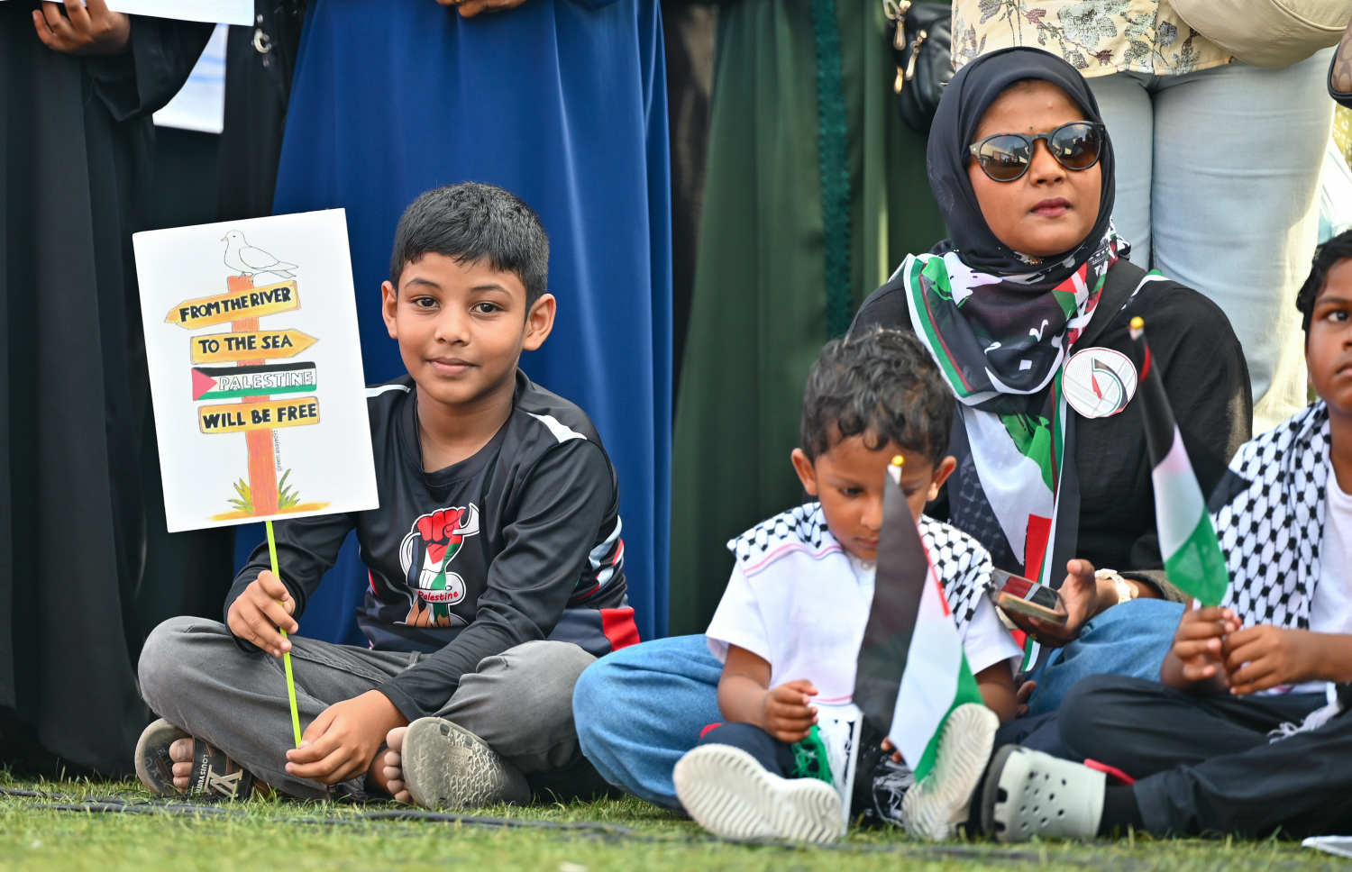 އިޒްރޭލުގެ ޖަރީމާތަކާ ދެކޮޅަށް މާލޭގައި ބޭއްވި ބޮޑު އެއްވުމުގައި ބައިވެރިވި ކުޑަކުދިންތަކެއް އެ ކުދިންގެ ބެލެނިވެރިޔާއާ އެކު ޕޯސްޓަރެއް ހިފައިގެން މާފަންނު ސްޓޭޑިއަމްގައި.--- ފޮޓޯ: ފަޔާޒު މޫސާ | މިހާރު