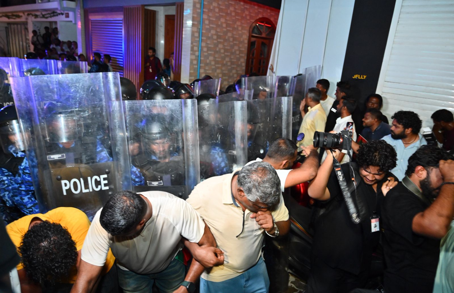 އެމްޑީޕީގެ ސަޕޯޓަރުން ފުލުހުންގެ ޝީލްޑް ކައިރީގައި މަޑުކޮށްލައިގެން.---ފޮޓޯ: ނިޝާން އަލީ| މިހާރު