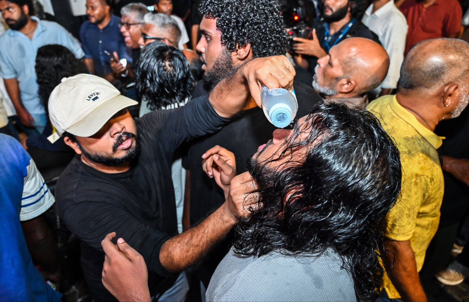 އިދިކޮޅު އެމްޑީޕީގެ ބޮޑު އެއްވުމުގެ ބައިވެރިން ފުލުހުންގެ އެންގުމާ ހިލާފަށް މަޖީދީ މަގުން ދާން މަސައްކަތް ކުރުމުން، އެ މީހުން ފަހަތަށް ޖައްސަން ފުލުހުން ޕެޕާސްޕްރޭ ޖެހުމާ ގުޅިގެން ލޮލަށް ފެން އަޅަނީ.---ފޮޓޯ: ފަޔާޒު މޫސާ| މިހާރު