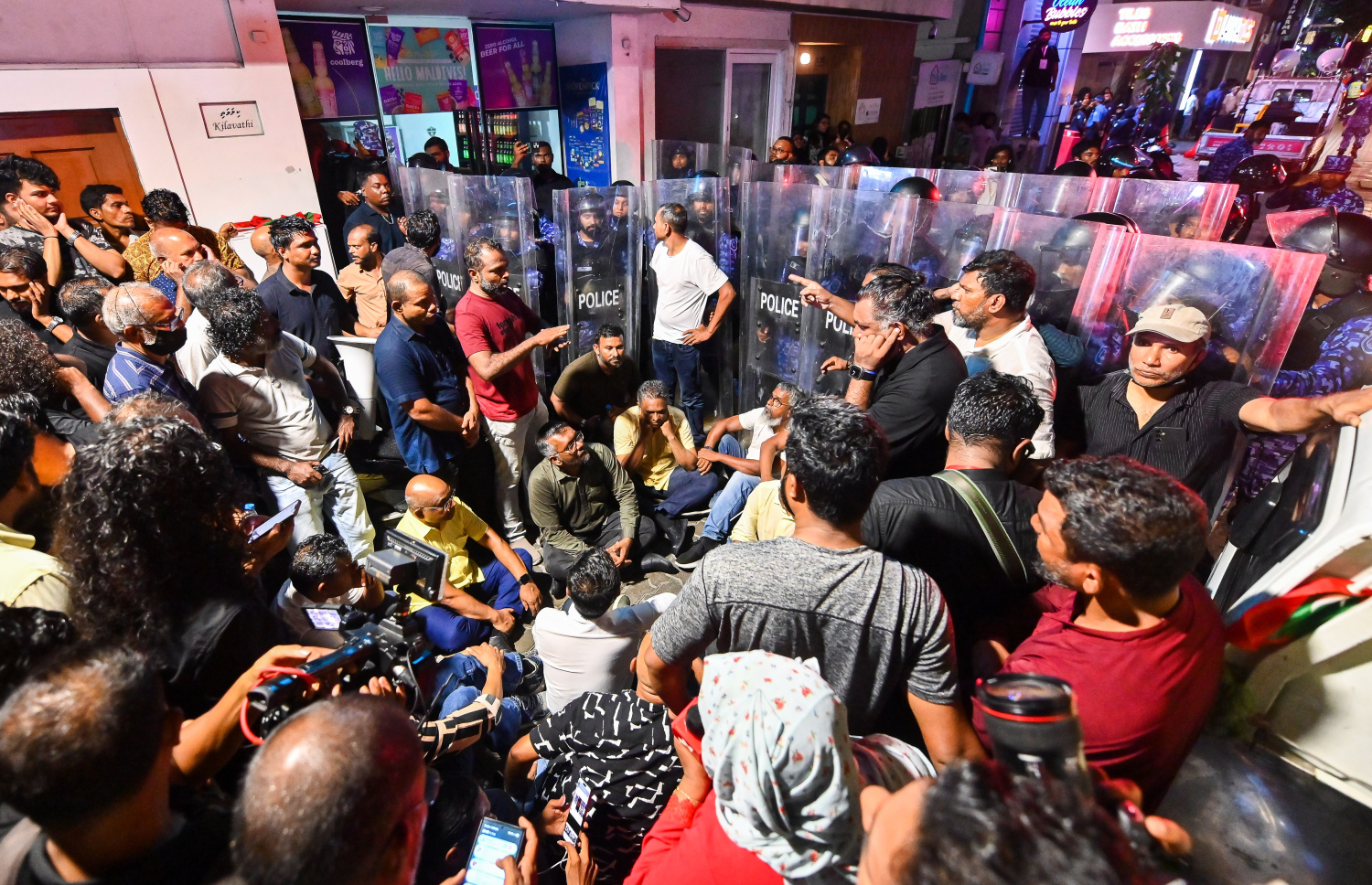 މަޖީދީ މަގުން އެމްޑީޕީގެ އެއްވުމުގެ ބައިވެރިން ކުރިއަށް ދާން ފުރުސަތު ނުލިބުމުން ކުރީގެ ރައީސް އިބްރާހިމް މުހައްމަދު ސޯލިހާއި އެ ޕާޓީގެ ލީޑަޝިޕްގެ ބޭފުޅުން އަދި އަދާލަތު ޕާޓީގެ ރައީސް ޝައިހު އިމްރާން އަބްދުﷲ ފުލުހުންގެ ޝީލްޑުތައް ކައިރީގައި އިށީނދެވަޑައިގެން: ފުލުހުން ބުނެފައި ވަނީ މި އެއްވުމަށް ހުއްދަ ދިނީ އަމީނީ މަގާއި ބޮޑުތަކުރުފާނު މަގުން ކުރިއަށް ދާން ކަމަށް.---ފޮޓޯ: ފަޔާޒު މޫސާ| މިހާރު