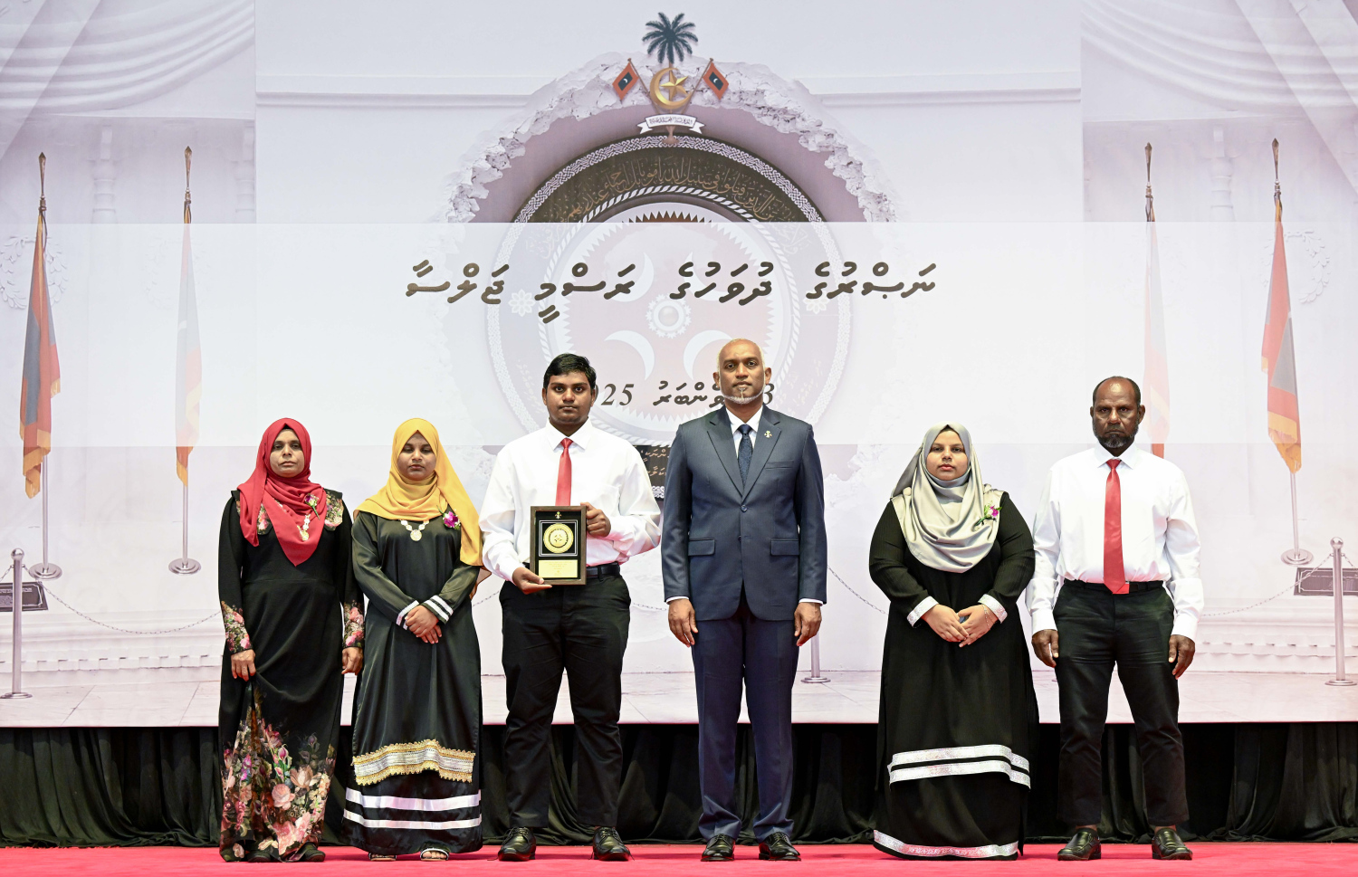 ނަސްރުގެ ދުވަސް ފާހަގަކުރަން މިއަދު ބޭއްވި ރަސްމީ ޖަލްސާގައި، ޝަހީދުވި މީހުންގެ އާއިލާއަށް ރައީސް ޑރ. މުއިއްޒު އެރުވި އައްޑަނައާއެކު، ފޮޓޯއަކަށް ހުއްޓިލައިގެން.-- ފޮޓޯ: ރައީސް އޮފީސް