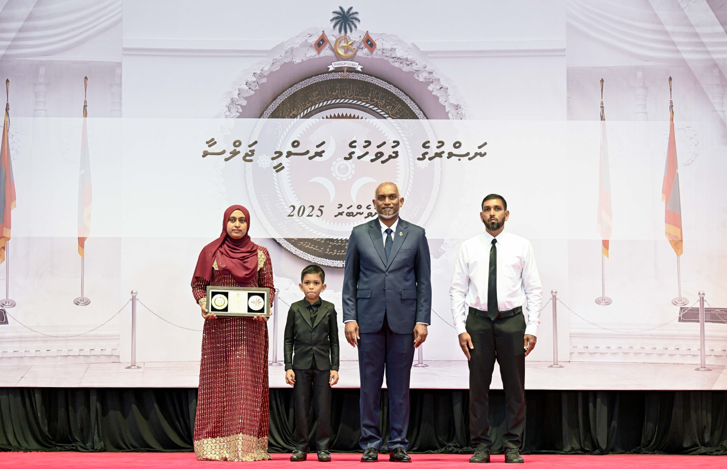 މި އަހަރުގެ ނަސްރުގެ ދުވަސް ފާހަގަކުރަން މިއަދު ބޭއްވި ރަސްމީ ޖަލްސާގައި، ނޮވެމްބަރު 3 ގެ ހަމަލާތަކުގައި ޝަހީދުވި މީހެއްގެ އާއިލާ އަށް ރައީސް. މުއިއްޒު އެރުވި އައްޑަނައާ އެކު، ފޮޓޯއަކަށް ހުއްޓިގެން.--- ފޮޓޯ: ރައީސް އޮފީސް