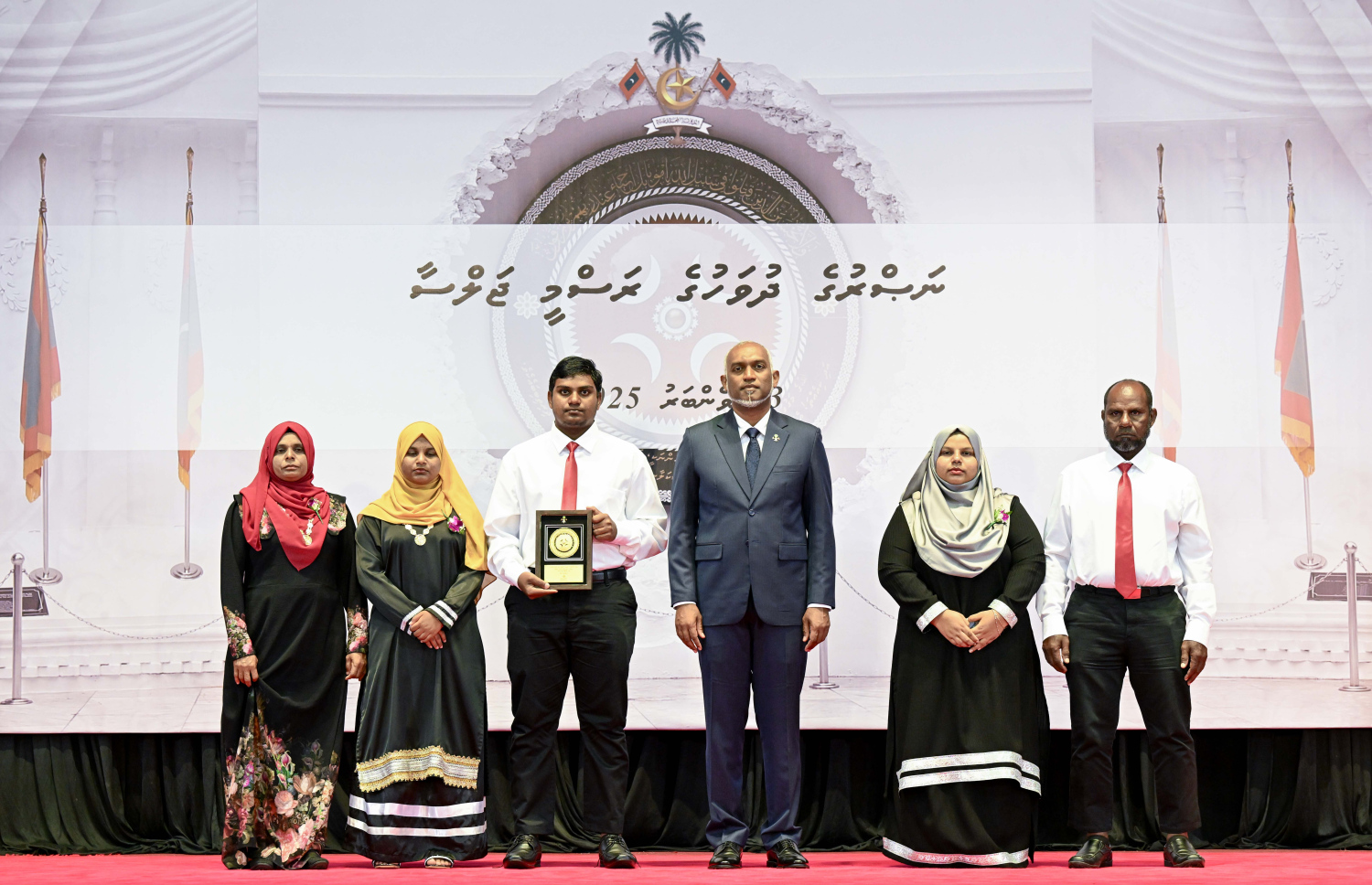 މި އަހަރުގެ ނަސްރުގެ ދުވަސް ފާހަގަކުރަން މިއަދު ބޭއްވި ރަސްމީ ޖަލްސާގައި، ނޮވެމްބަރު 3 ގެ ހަމަލާތަކުގައި ޝަހީދުވި މީހެއްގެ އާއިލާ އަށް ރައީސް މުއިއްޒު އެރުވި އައްޑަނައާ އެކު، ފޮޓޯއަކަށް ހުއްޓިގެން.--- ފޮޓޯ: ރައީސް އޮފީސް