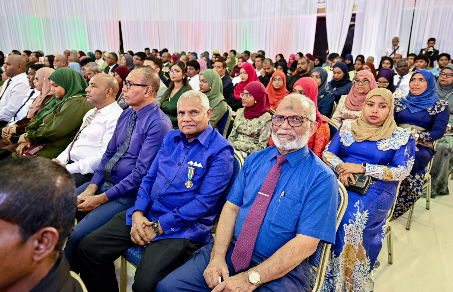 ސޯޝަލް ސެންޓަރުގައި މިއަދު ހެނދުނު ބޭއްވި 57 ވަނަ ޖުމްހޫރީ ދުވަހުގެ ރަސްމީ ޖަލްސާގައި ބައިވެރިވެވަޑައިގެންނެވި ބައެއް ބޭފުޅުން.-.-- ފޮޓޯ: ރައީސް އޮފީސް