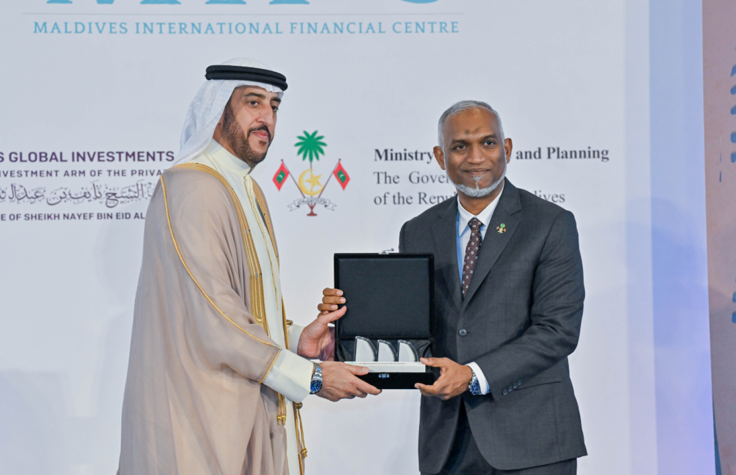ދިވެހި ސަރުކާރާއި އެމްބީއެސް ގްލޯބަލް އިންވެސްޓްމަންޓްސް އިން 8.8 ބިލިއަން އެމެރިކާ ޑޮލަރުގެ މޯލްޑިވްސް އިންޓަނޭޝަނަލް ފައިނޭންޝަލް ސެންޓަރު ގާއިމުކުރުމުގެ އެއްބަސްވުމުގައި މި އަހަރުގޭ މޭ މަހުގެ ފަސްވަނަ ދުވަހު ސޮއިކުރުމަށް ފަހު، އެމްބީއެސް ގްލޯބަލް އިންވެސްޓްމަންޓްސްގެ ފަރާތުން ރައީސް މުއިއްޒަށް ހަދިޔާއެއް އަރުވަނީ. --- ފޮޓޯ: ރައީސް އޮފީސް