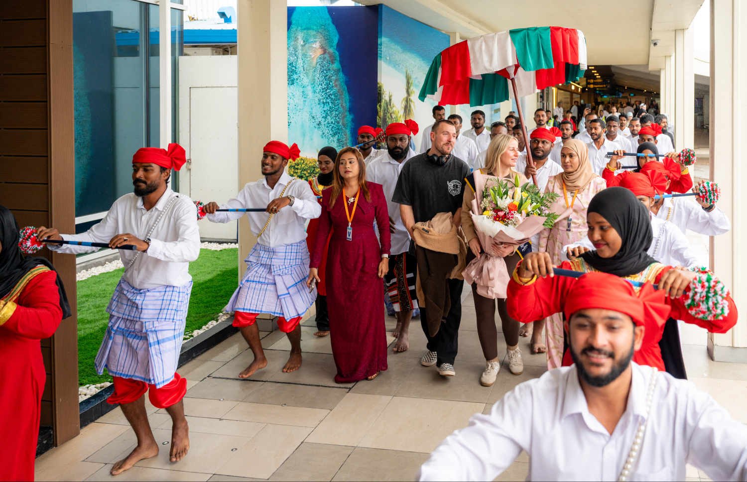 ރާއްޖެ އަށް ޒިޔާރަތްކުރި ދެ މިލިއަން ވަނަ ޓޫރިސްޓުގެ ޝަރަފު ހޯދި އިނގިރޭސި ވިލާތުގެ ބެތަނީ ސާރާ ކާސްވެލް އަށް ދިވެހި ސަގާފީ ހަރަކާތަކުން މަރުހަބާ ކިޔަނީ.---ފޮޓޯ: ނިޝާން އަލީ| މިހާރު