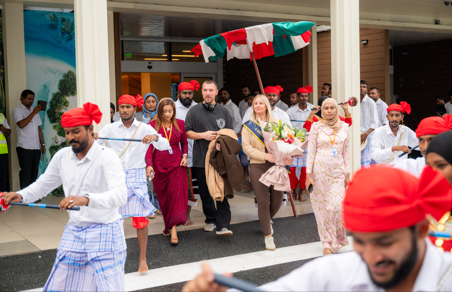 ރާއްޖެ އަށް ޒިޔާރަތްކުރި ދެ މިލިއަން ވަނަ ޓޫރިސްޓުގެ ޝަރަފު ހޯދި އިނގިރޭސި ވިލާތުގެ ބެތަނީ ސާރާ ކާސްވެލް އަށް ދިވެހި ސަގާފީ ހަރަކާތަކުން މަރުހަބާ ކިޔަނީ.---ފޮޓޯ: ނިޝާން އަލީ| މިހާރު