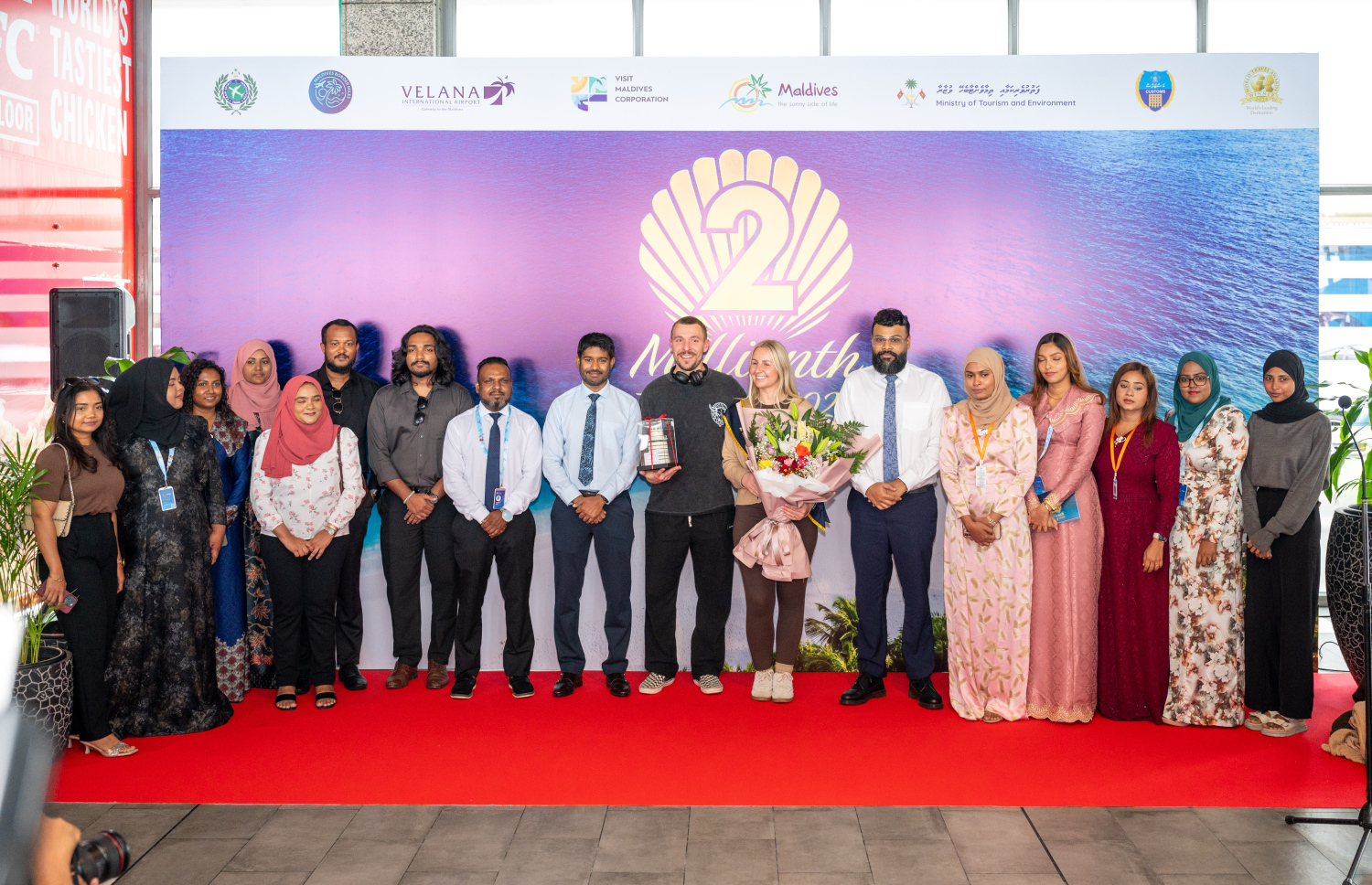 ރާއްޖެ އަށް ޒިޔާރަތްކުރި ދެ މިލިއަން ވަނަ ޓޫރިސްޓުގެ ޝަރަފު ހޯދި އިނގިރޭސި ވިލާތުގެ ބެތަނީ ސާރާ ކާސްވެލްއާ އެކު، ވިޒިޓް މޯލްޑިވްސްގެ އިސްވެރިންނާއި ބައެއް މުވައްޒަފުން ފޮޓޯއެއް ނަގަނީ.---ފޮޓޯ: ނިޝާން އަލީ| މިހާރު