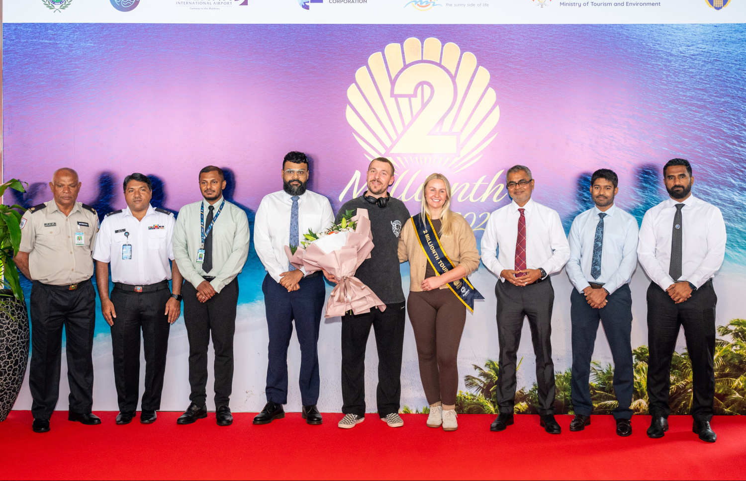 ރާއްޖެ އަށް ޒިޔާރަތްކުރި ދެ މިލިއަން ވަނަ ޓޫރިސްޓުގެ ޝަރަފު ހޯދި އިނގިރޭސި ވިލާތުގެ ބެތަނީ ސާރާ ކާސްވެލްއާ އެކު، ޓޫރިޒަމް މިނިސްޓަރު ތޯރިގާއި އެމްއެމްޕީއާރުސީގެ މެނޭޖިން ޑިރެކްޓަރު އިބްރާހީމް ޝިއުރީ އާއި އިމިގްރޭޝަން އަދި ކަސްޓަމްސްގެ ބައެއް އިސްވެރިން ފޮޓޯއެއް ނަންގަވަނީ.--- ފޮޓޯ: ނިޝާން އަލީ | މިހާރު