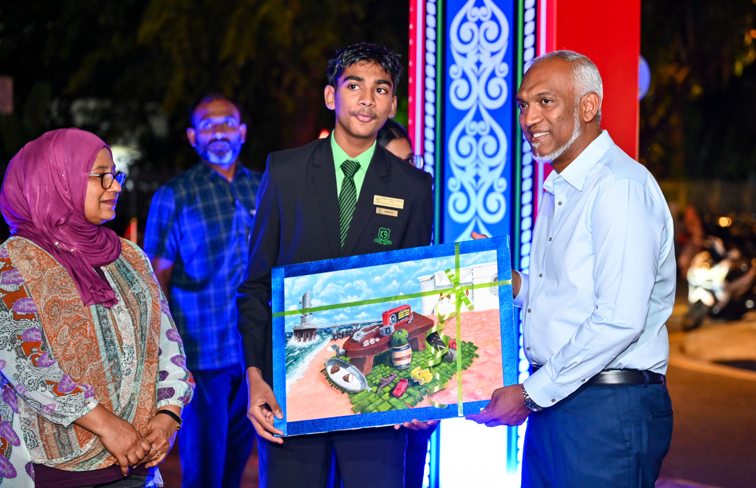 ހެންވޭރުގެ ރައްޔިތުންނާ ބައްދަލު ކުރެއްވުމަށް ކަލާފާނު ސްކޫލްގައި ބޭއްވި ޖަލްސާއަށް ރައީސް ޑރ. މުހައްމަދު މުއިއްޒު ވަޑައިގަތުމުން އެ ސްކޫލުގެ ދަރިވަރަކު ރައީސަށް ކުރެހުމެއް ހަދިޔާ ކުރަނީ -- ފޮޓޯ: ފަޔާޒު މޫސާ | މިހާރު