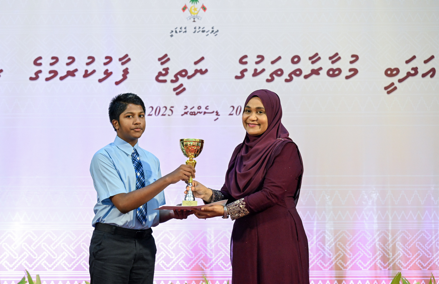 ގައުމީ އަދަބީ މުބާރާތްތަކާއި އަތުލިޔުމުގެ މުބާރާތުން ވަނައަކަށް ހޮވުނު ދަރިވަރަކަށް ފަސްޑްލޭޑީ ސާޖިދާ މުހައްމަދު އިނާމް ހަވާލުކޮށްދެއްވަނީ --- ފޮޓޯ/ރައީސް އޮފީސް