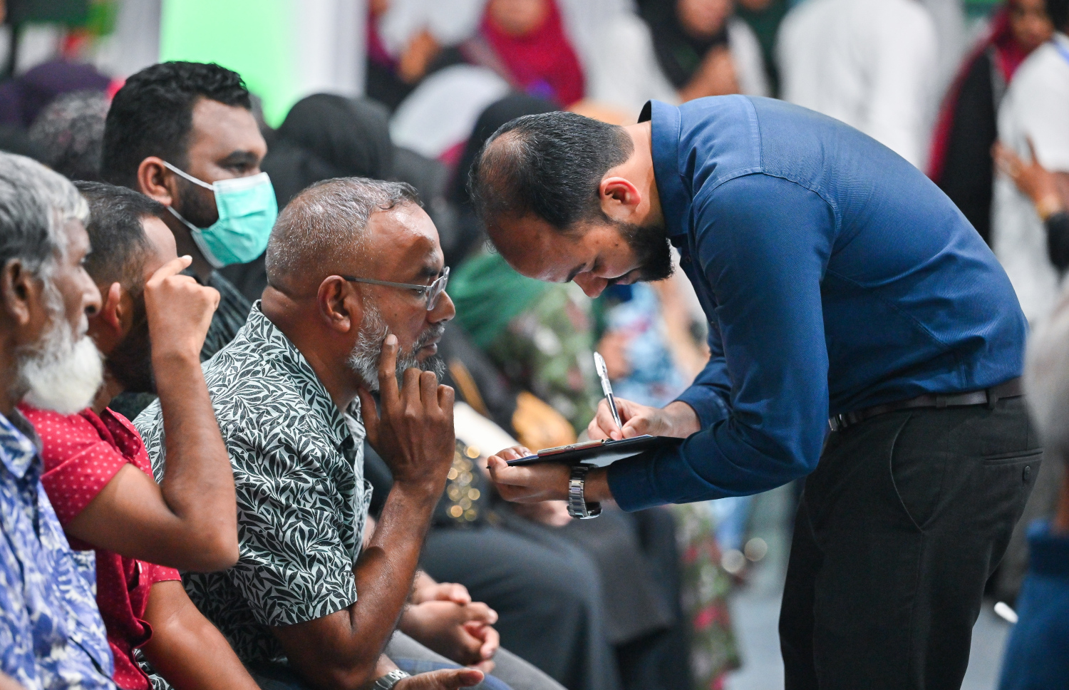 ހުޅުމާލޭ ފުރަތަމަ ފިޔަވަހީގެ ރައްޔިތުންނާ ބައްދަލުކުރައްވަން ރައީސް މުއިއްޒު ބޭއްވެވި ބައްދަލުވުމުގައި އާންމުންގެ މީހަކު ސުވާލުކުރަން ނަން ނޯޓް ކުރަނީ --- މިހާރު ފޮޓޯ/ފަޔާޒު މޫސާ