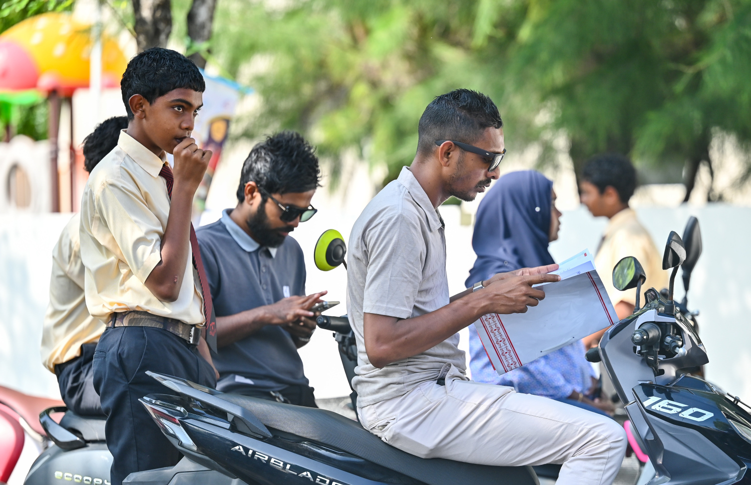 ހުޅުމާލޭގެ ޣާޒީ ސްކޫލްގެ ދަރިވަރެއްގެ ބެލެނިވެރިޔާ ސްކޫލް ބޭރުގައި ރިޕޯޓް ފޯމު ބަލަނީ.--- ފޮޓޯ: ފަޔާޒު މޫސާ | މިހާރު