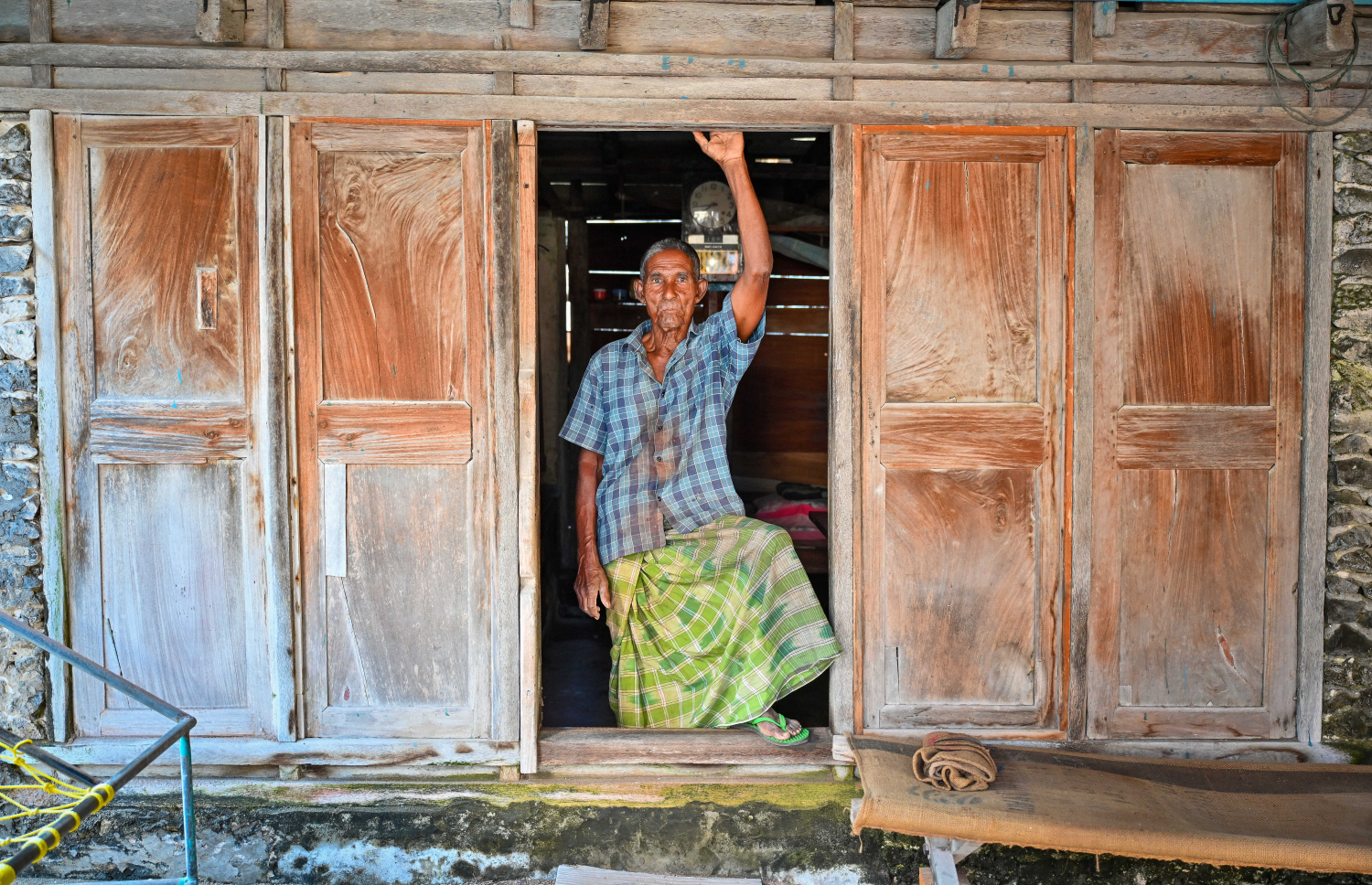 ތަރިޖެހިގޭގެ ދޮރުމަތީ އަލިބެ ފޮޓޯއަކަށް ހުއްޓިލައިގެން: އެ ގޭގައި އެކަނި ދިރިއުޅެން ޖެހުނު ނަމަވެސް، އަލިބެއަށް އެއީ މައިންބަފައިންގެ ހަނދާންތަކާ އެކު ހިތްހަމަޖެހުން ލިބޭ ކަމެއް.-- ފޮޓޯ: ފަޔާޒު މޫސާ | މިހާރު