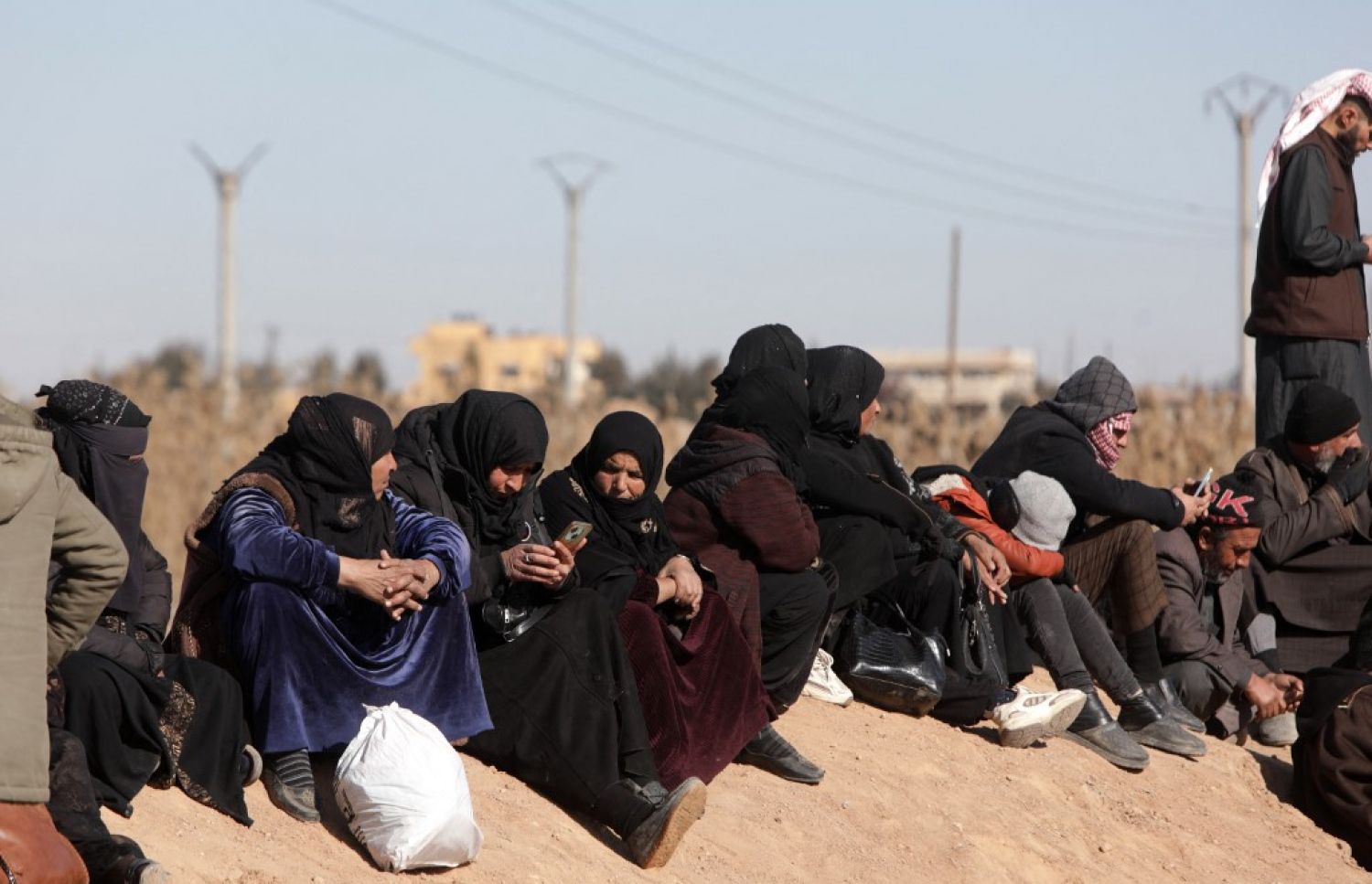 އަލް ހައުލް ރެފިއުޖީ ކޭމްޕު ބޭރުގައި އެ ތަނުގައި އުޅޭ ބައެއް މީހުންގެ އާއިލާތަކުގެ މީހުން މަޑުކޮށްލައިގެން. -- ފޮޓޯ: އޭއެފްޕީ