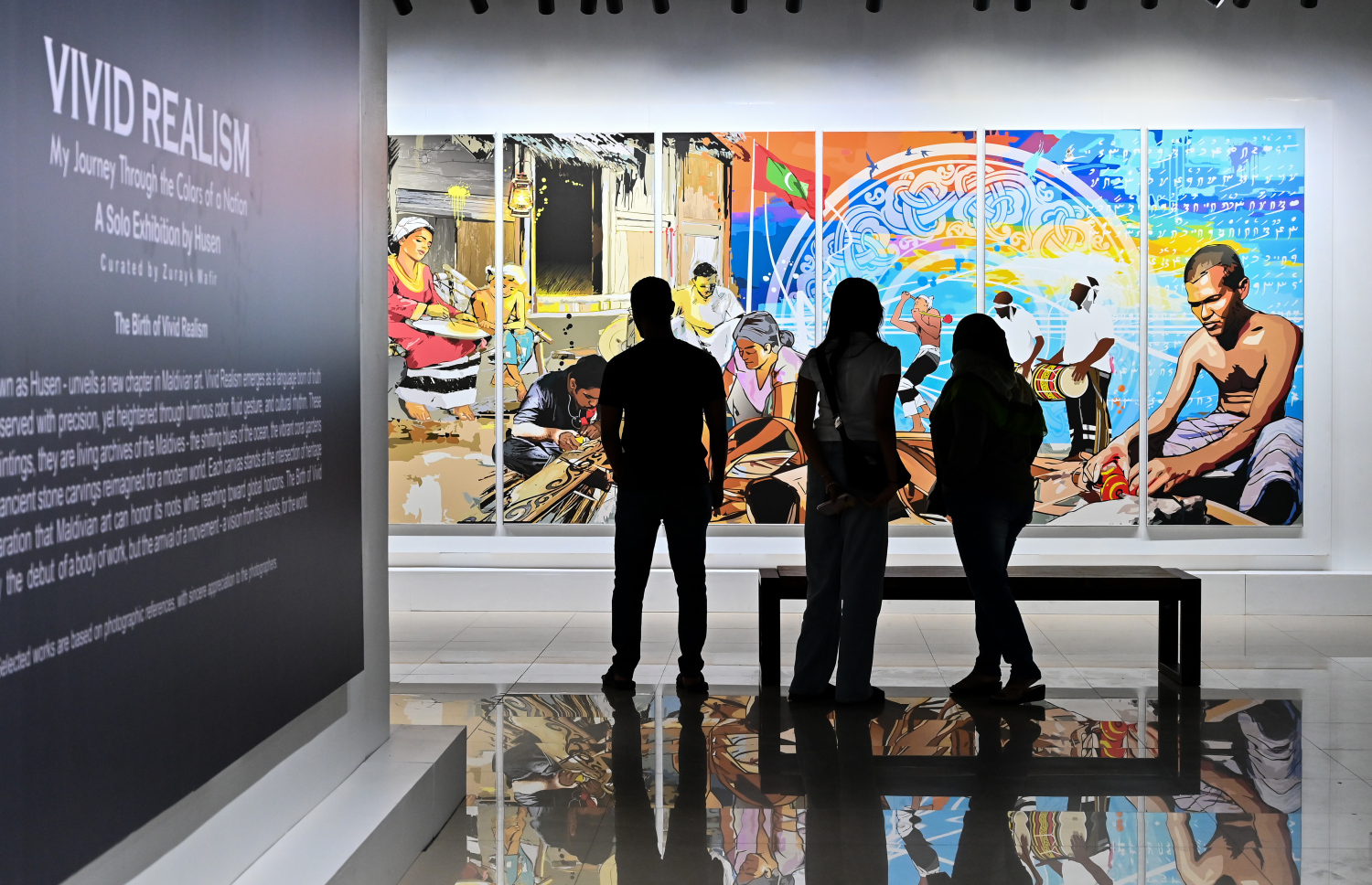 ކުރެހުންތެރިޔާ ހުސައިން އަލީ މަނިކުގެ "ވިވިޑް ރިއަލިޒަމް - ބައި ހުސައިން" އާޓް އެގްޒިބިޝަންނަށް ޒިޔާރަތްކުރި ބަޔަކު ކުރެހުންތައް ބަލައިލަނީ.-- ފޮޓޯ: ފަޔާޒު މޫސާ | މިހާރު