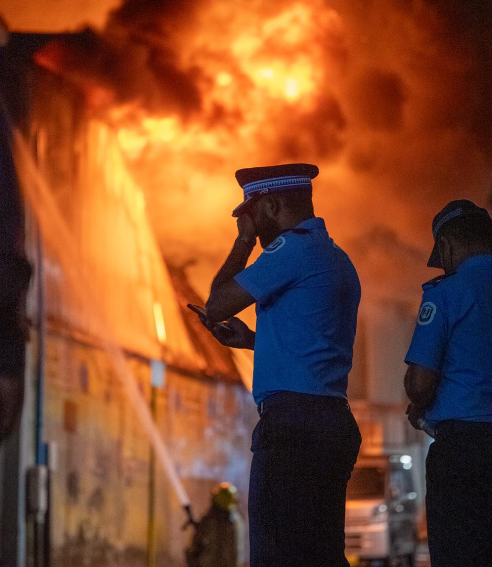 ކެމިކަލް އާއި ގަސްކާނާ ހުންނަ ގުދަނުގައި ރޯވެ އަނދަމުން ދާއިރު ސިފައިން އަލިފާން ނިއްވަން މަސައްކަތްކުރަނީ އަދި އެތަނުގެ ކައިރީގައި ފުލުހުންގެ ބަޔަކު. -- ފޮޓޯ: ނިޝާން އަލީ / މިހާރު