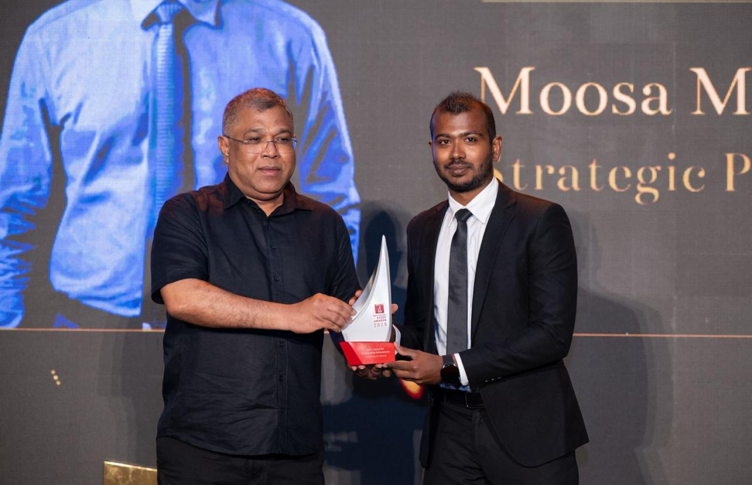 ބީއެމްއެލްގެ ހެޑް އޮފް ސްޓްރެޓެޖީ އެންޑް ޗޭންޖު، މޫސާ މުންސިފް އަހުމަދުއާ، އެ ބޭންކުގެ އެމްޑީ ޝަރީފު ރޭ އެވޯޑު ހަވާލު ކޮށްދެއްވަނީ.---ފޮޓޯ: ބީއެމްއެލް