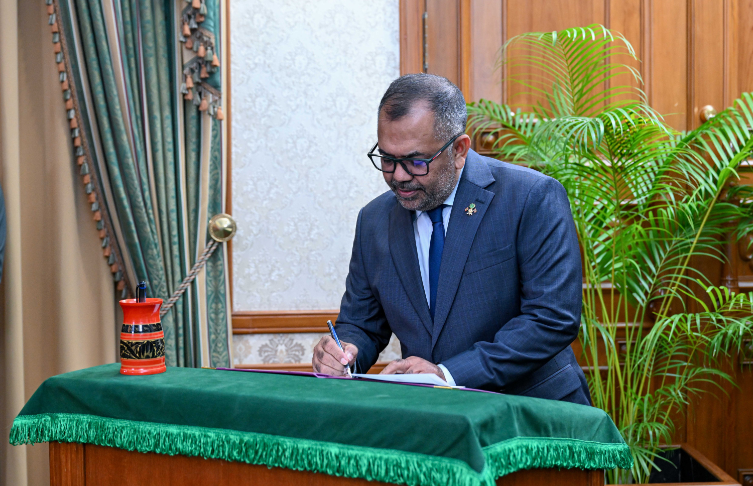 ފިނޭންސް އެންޑް ޕަބްލިކް އެންޓަޕްރައިސަސް މިނިސްޓަރަކަމަށް އައްޔަންކުރެއްވި މޫސާ ޒަމީރު ހުވާގެ އިގުރާރުގައި ސޮއިކުރައްވަނީ.--- ފޮޓޯ: ރައީސް އޮފީސް