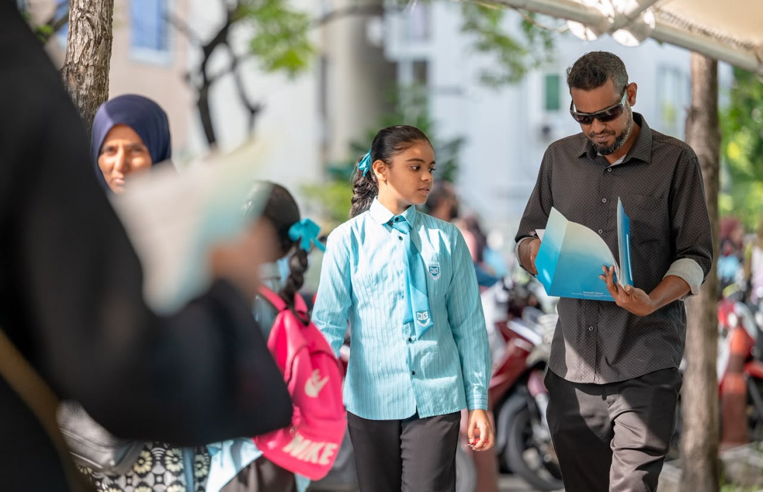ރެހެންދީ ސްކޫލުގެ ދަރިވަރަކު ބެލެނިވެރިއަކާއެކު ރިޕޯޓުފޮތް ހިފައިގެންދަނީ-- ފޮޓޯ: ފަޔާޒް މޫސާ / މިހާރު
